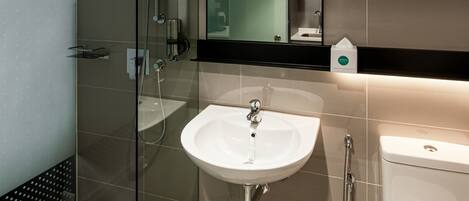 Une salle de bain moderne avec une douche à parois de verre, un lavabo blanc et des toilettes.