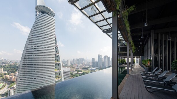 A modern building with a unique spiral design, a rooftop pool, and a view of the cityscape. - Komune Living (Kuala Lumpur)