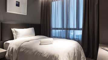 Una camera d'albergo moderna con un letto grande, un comodino, un quadro incorniciato appeso al muro e una finestra con tende.