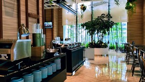 A modern hotel lobby with a buffet area, a coffee machine, and a TV screen. - Komune Living (Kuala Lumpur)