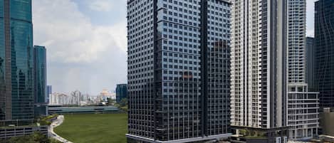 A high-rise building with a modern architectural design, featuring a prominent glass facade and a rooftop garden.
