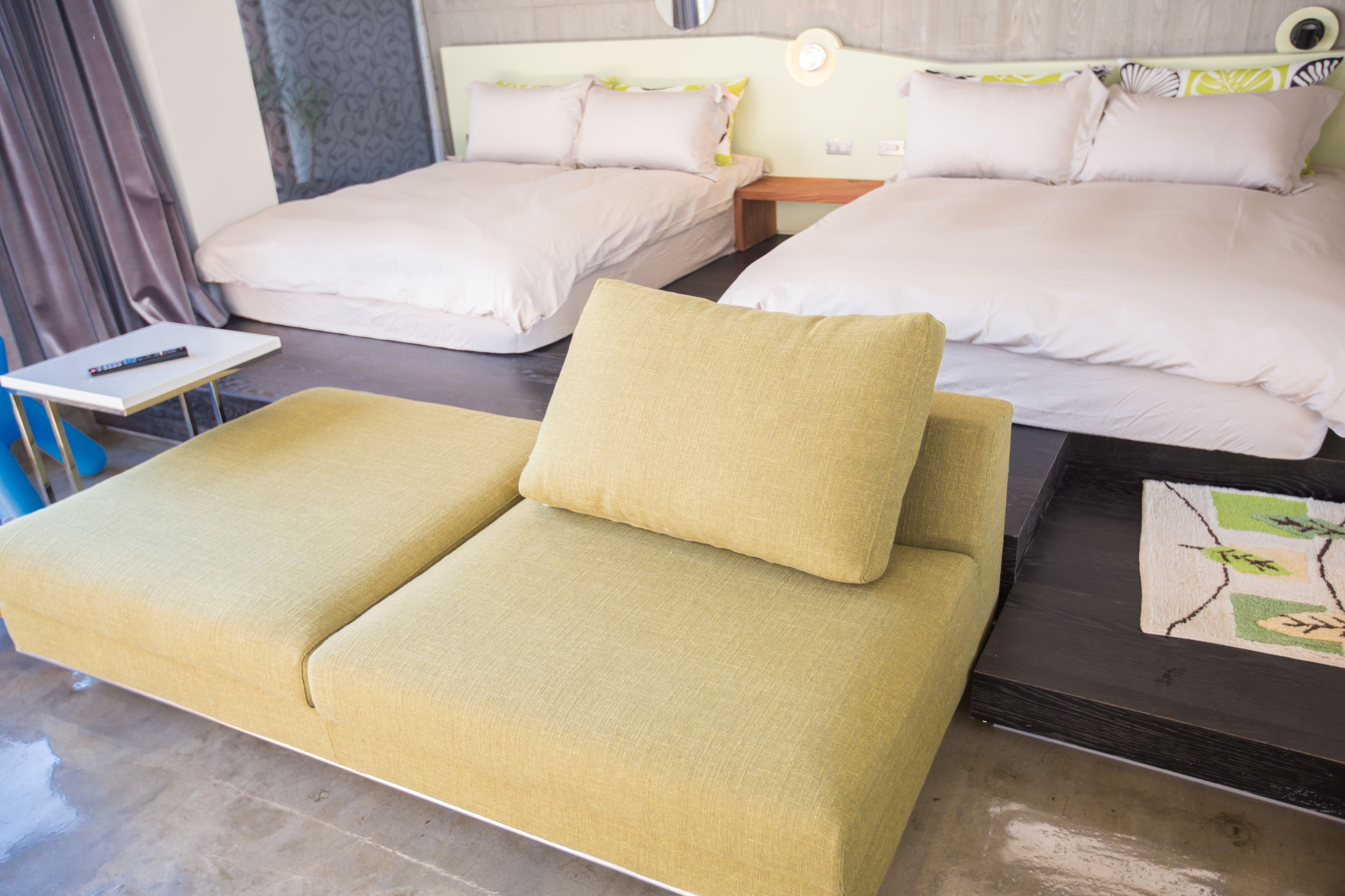 A hotel room with a large bed, a sofa, and a small table with a remote control.