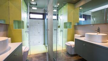 A modern bathroom with a glass-enclosed shower, two sinks, and a large mirror.