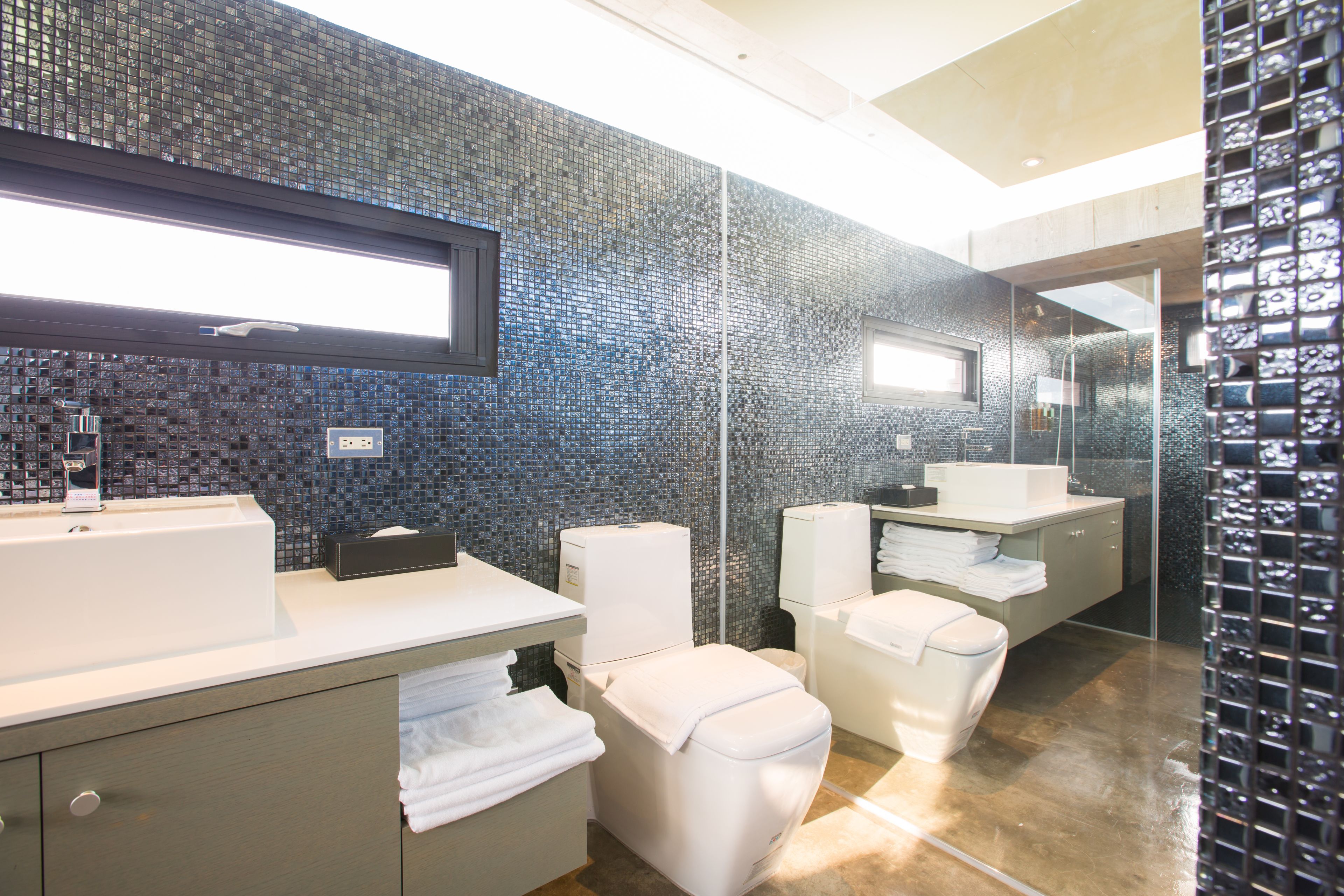 A modern bathroom with a large mirror, a white sink, and a toilet.