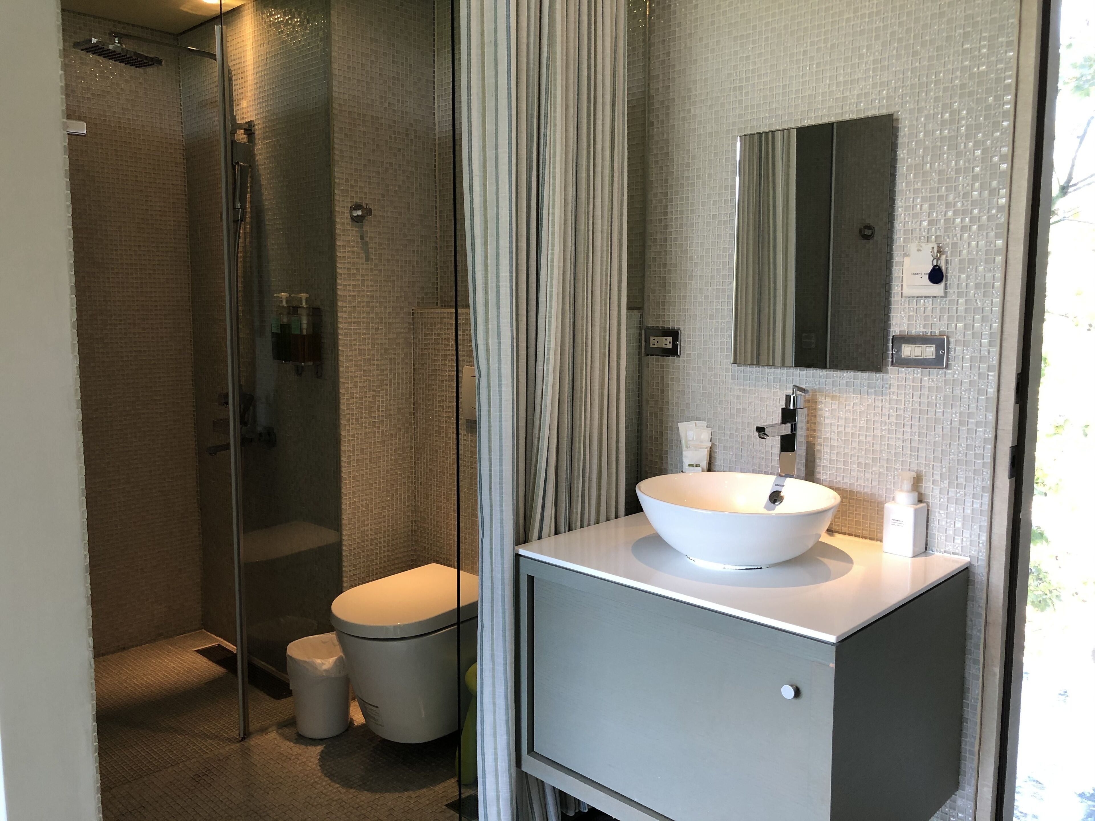 A modern bathroom with a glass-enclosed shower, a white sink, and a large mirror.