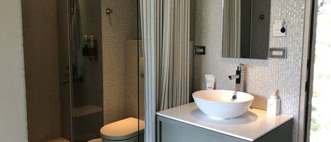 A modern bathroom with a glass-enclosed shower, a white sink, and a large mirror.