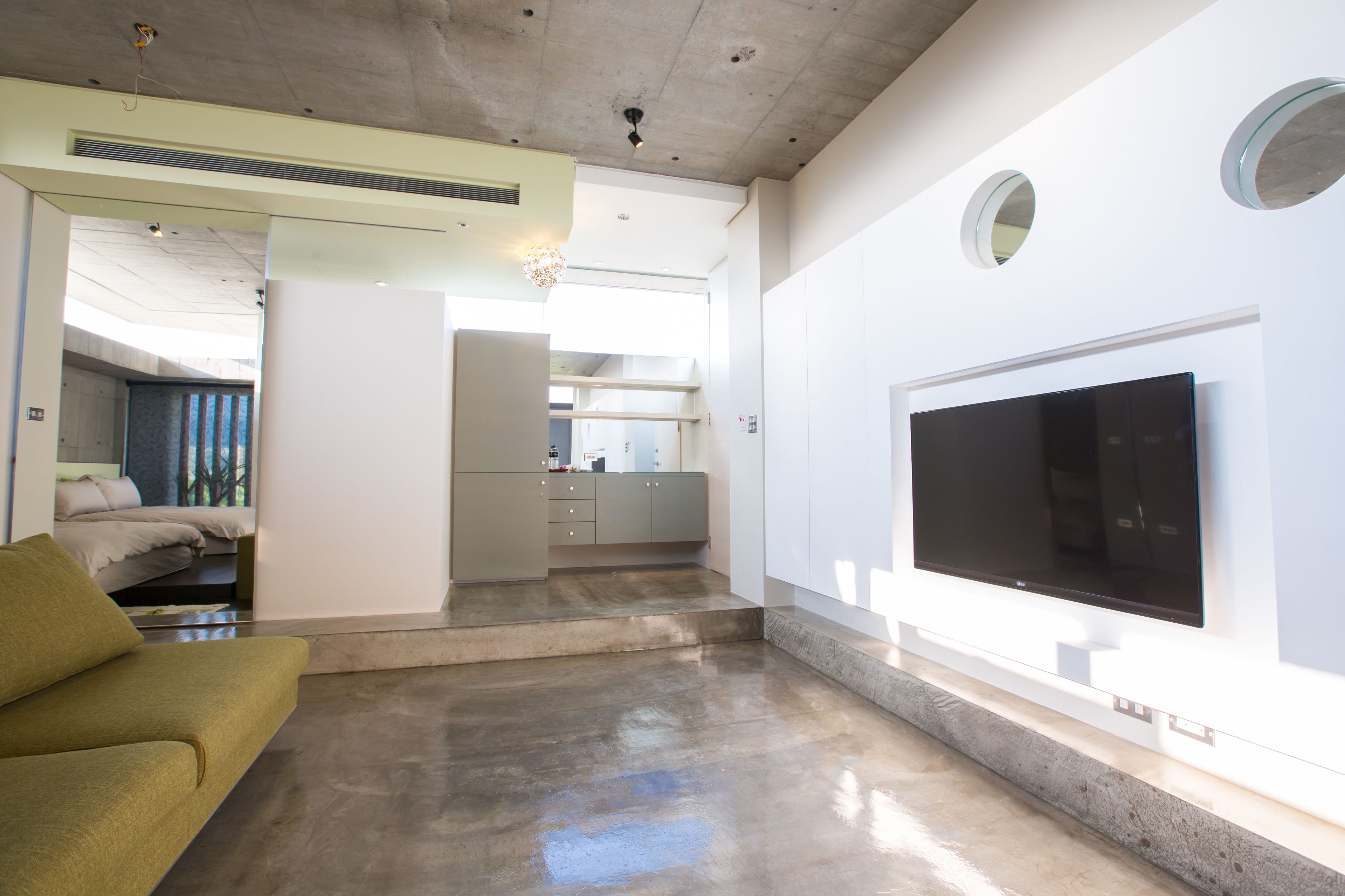 Una sala de estar moderna con un televisor de pantalla plana grande, un sofá y una zona de cocina al fondo.
