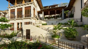 Un edificio de varios pisos con balcones, una escalera y plantas en macetas.