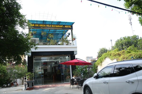 A building with a sign reading "IAM COC GREEN FIELD RESTAURANT & HOSTEL".