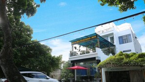 A white building with a blue awning and a red umbrella outside. - TamCoc Green field Hostel (Nam Hoa Lu)