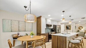 Een moderne keuken met een centraal eiland, houten kasten en hanglampen.