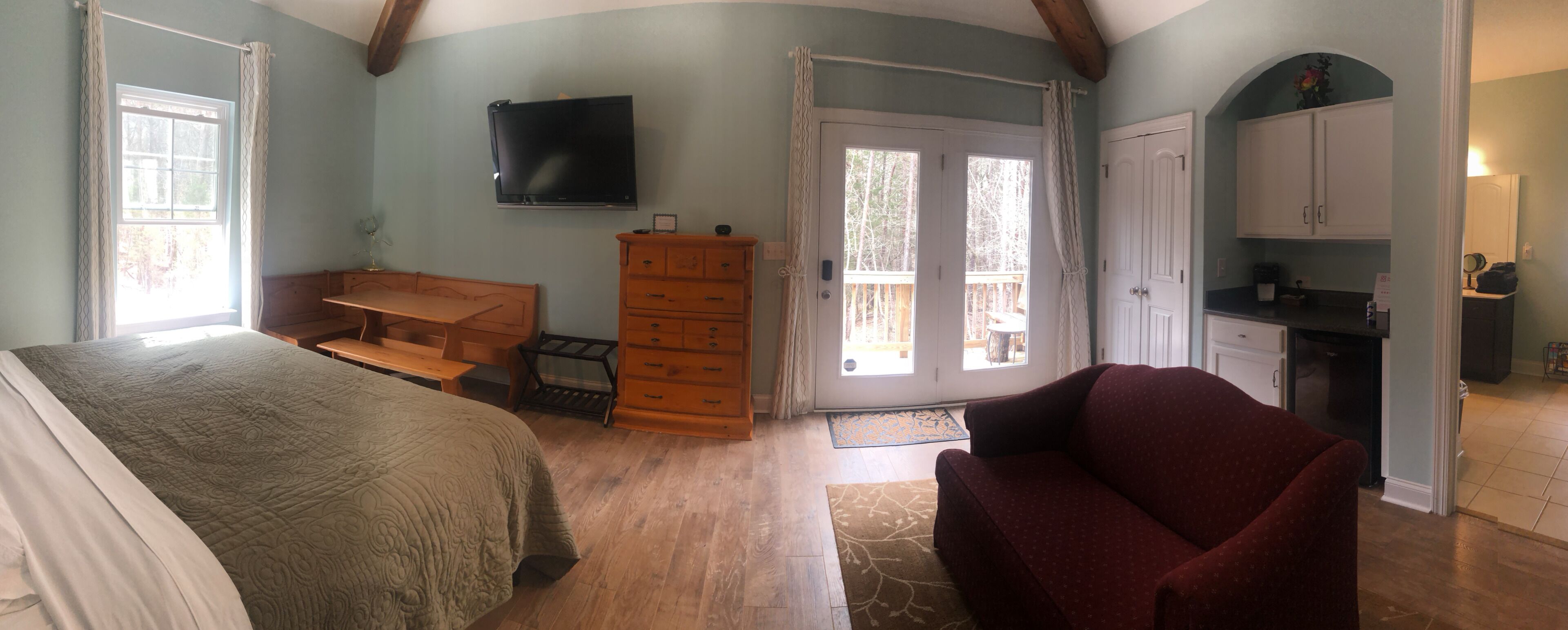 A bedroom with a bed, dresser, and a TV on the wall.