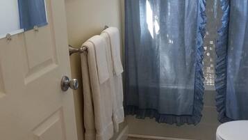 Ein Badezimmer mit Toilette, Waschbecken, Spiegel, Handtuchhalter und einer Duschvorhang.