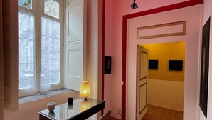 A room with a dining table, a chair, a window with curtains, and a red ceiling.