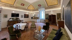 A spacious living area with a high ceiling, a dining table, and a sofa.