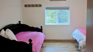 Um quarto com uma cama, uma janela e um letreiro com a palavra 'welcome'.