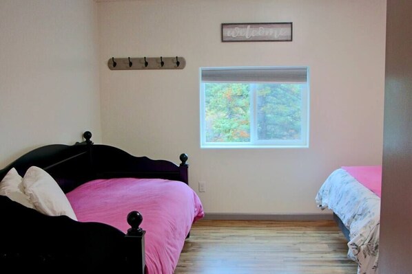 A bedroom with a bed, a window, and a 'welcome' sign.