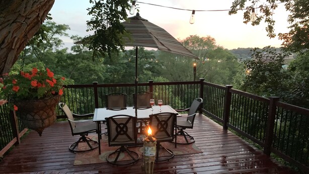 An outdoor deck with a table and chairs, a hanging light fixture, and a potted plant. - Charming Hilltop Home with City View (Chippewa Falls)