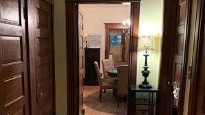 A hallway with wooden doors, a dining area with a table and chairs, and a lamp on a side table. - Charming Hilltop Home with City View (Chippewa Falls)
