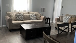 Un salon avec un canapé beige, une table basse et une table à manger avec des chaises.