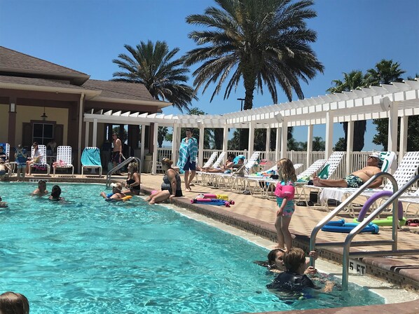 Relax by the pool surrounded by palm trees and shaded by a pergola.