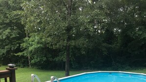 Ein Pool im Freien mit Holzterrasse und Metallleiter.