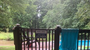 Ein Poolbereich mit geschlossenem Tor, Holzeinstiegsstufen zu einer Terrasse und einem blauen Pool.