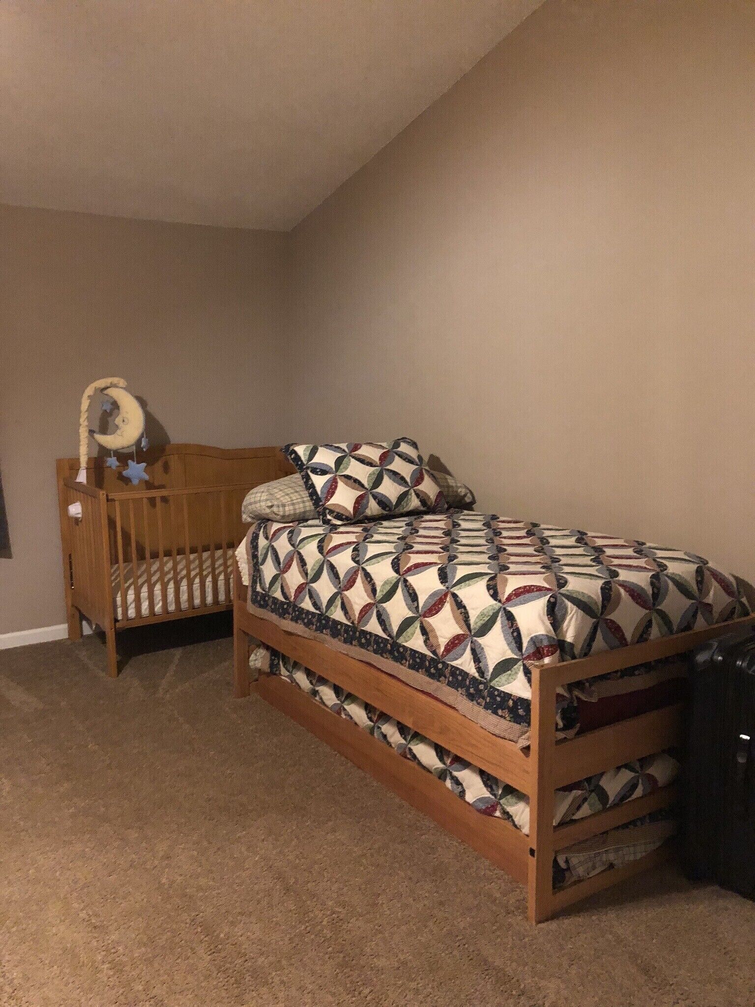 A bedroom with a wooden bed, a crib, and a wall-mounted shelf.