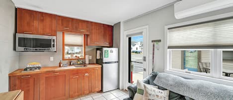 A compact kitchen with wooden cabinets, a microwave, and a refrigerator.