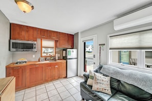 A compact kitchen with wooden cabinets, a microwave, and a refrigerator. - WildWoof Beach Bungalow @ North Wildwood - No Pet Fees! (North Wildwood)
