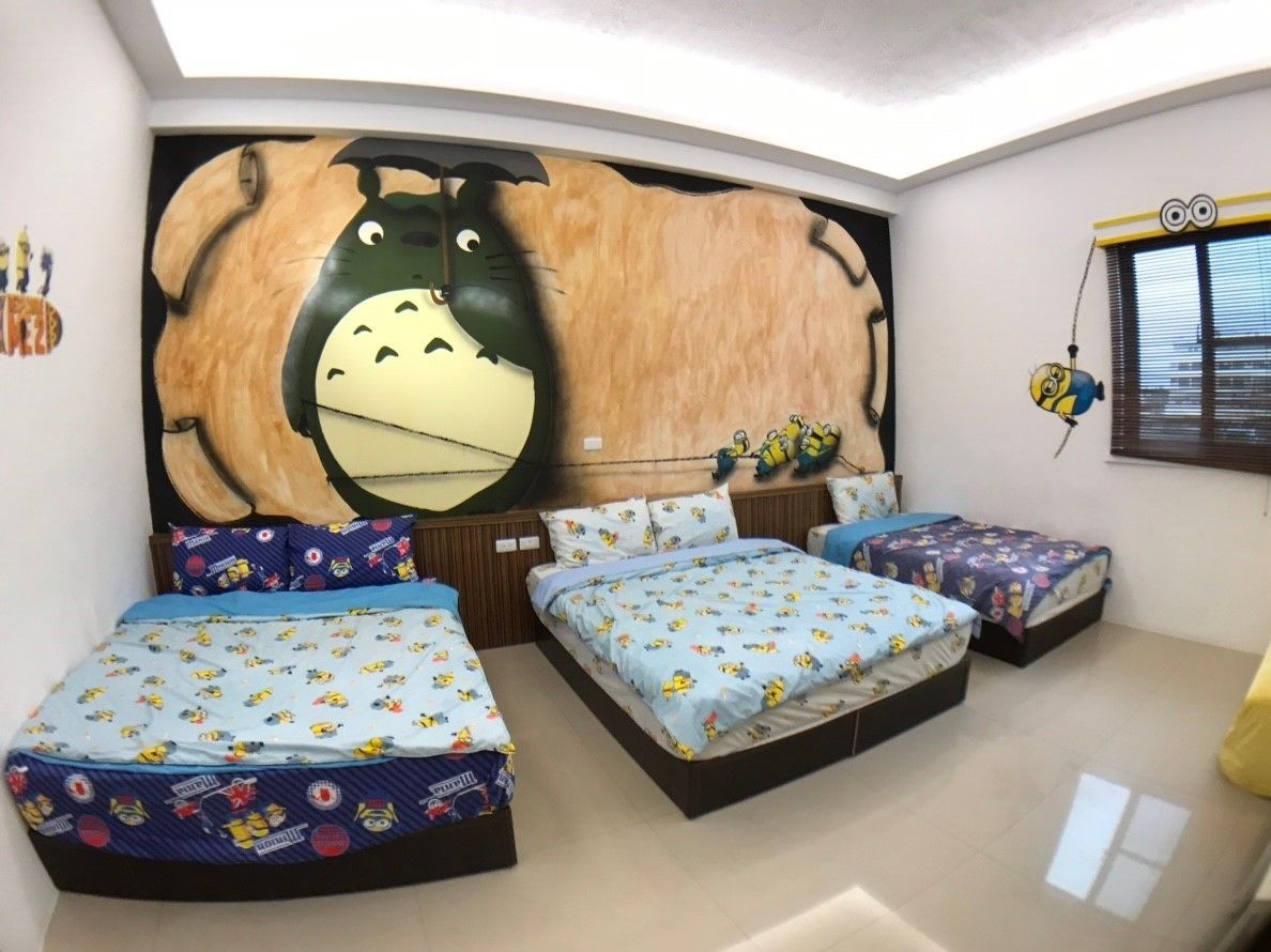 A bedroom with a large mirror, three beds with matching bedding, and a Minion-themed window decal.