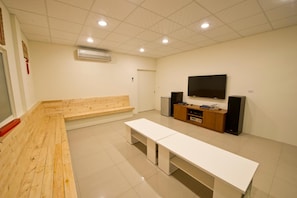 A modern room with a wooden bench, a white table, a TV, and a speaker system. - Donggang Neptune Hall (Donggang)