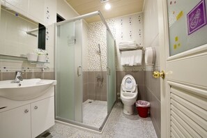 A bathroom with a glass-enclosed shower, a white sink, a toilet, and a trash bin. - Donggang Neptune Hall (Donggang)