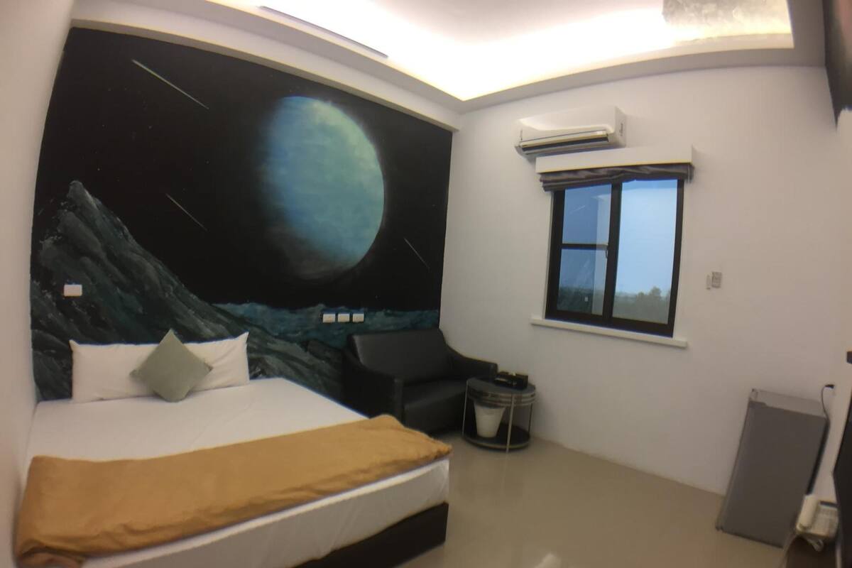A bedroom with a bed, a night sky mural, a window, and an air conditioning unit.