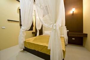 Una habitación con cama, mesita de noche, lámpara de pared y espejo.