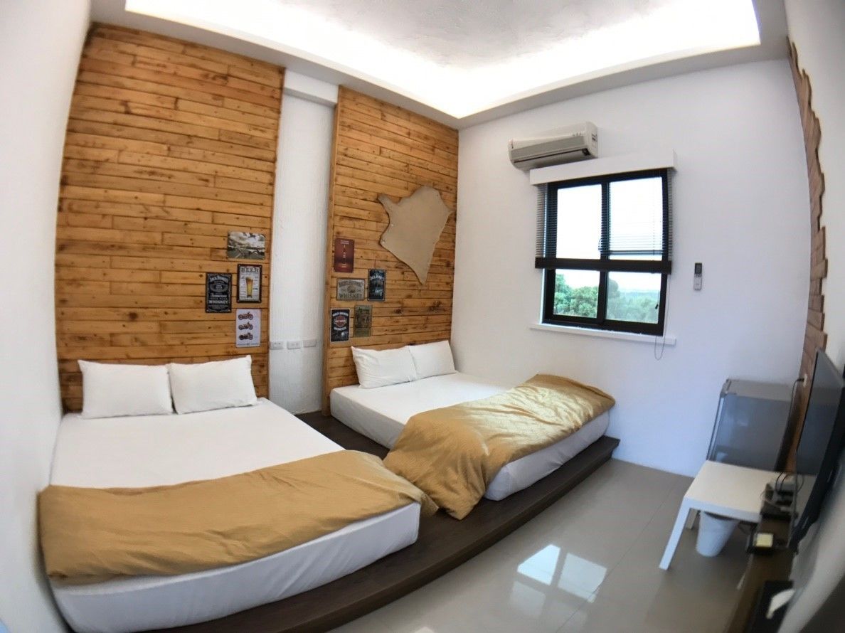 Una habitación con dos camas, una pared de madera, una ventana con vistas y un escritorio con silla.