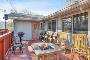 A covered outdoor deck with a fire pit, seating, and a barbecue grill. - Downtown Cabin w/Ball Court, Hot Tub, & Firepit (GATLINBURG)