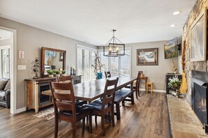 A dining area with a wooden table and chairs, a chandelier, and a fireplace. - Downtown Cabin w/Ball Court, Hot Tub, & Firepit (GATLINBURG)