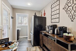 Una cocina funcional con un refrigerador negro, armarios de madera y una estación para café.