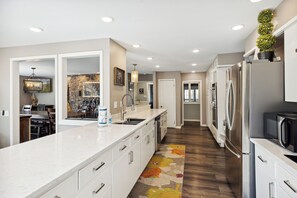 A modern kitchen with white cabinetry, stainless steel appliances, and a central island. - Downtown Cabin w/Ball Court, Hot Tub, & Firepit (GATLINBURG)