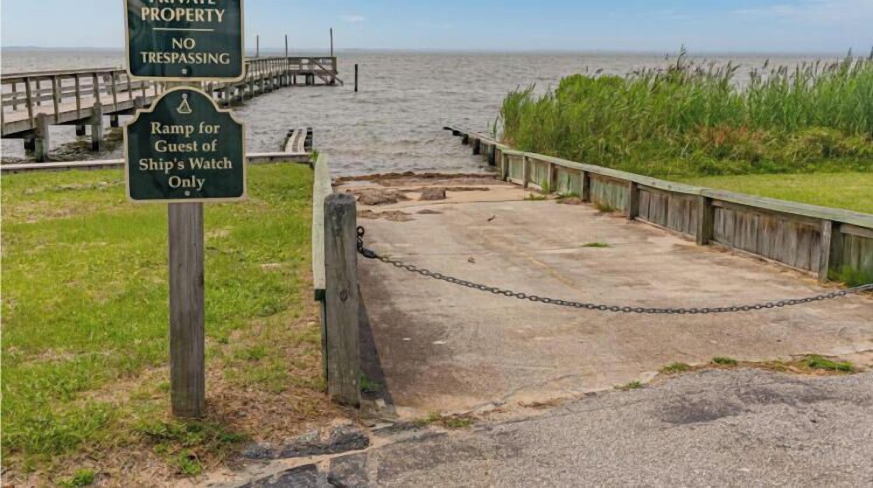 A private property with a no trespassing sign, a ramp for guests of a ship's watch, and a chain-link fence.