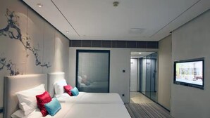 Ein modernes Hotelzimmer mit zwei Betten, einem großen Fenster und Blick auf die Stadt.