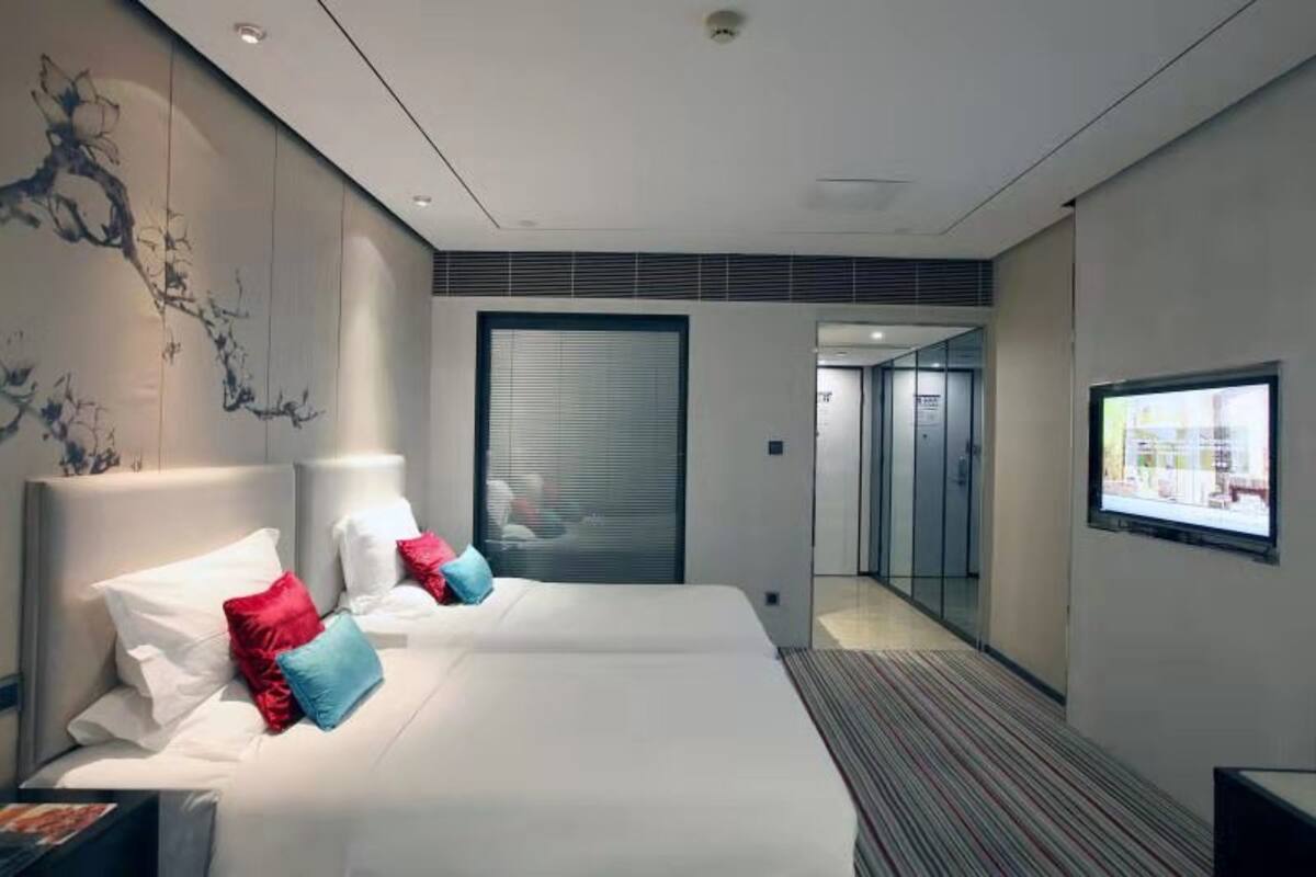 Ein modernes Hotelzimmer mit zwei Betten, einem großen Fenster und Blick auf die Stadt.