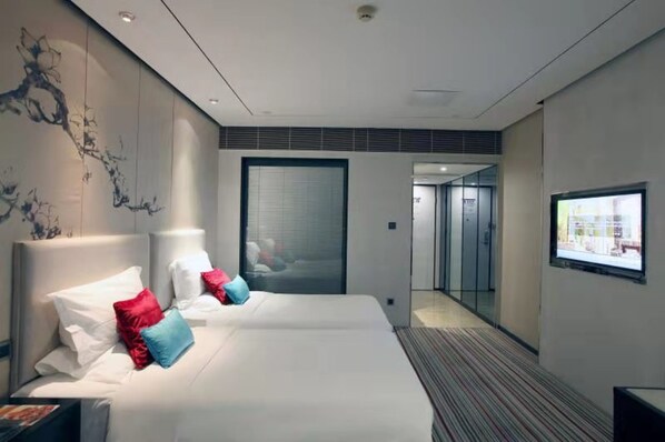 Una habitación de hotel moderna con dos camas, un ventanal grande y vistas a la ciudad.