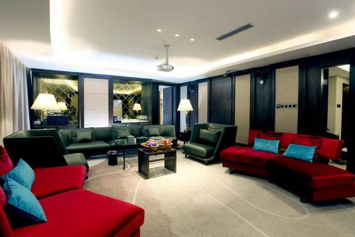 Ein modernes Wohnzimmer mit dunklen Wänden, einem roten Sofa, einem grünen Sofa und einem roten Sessel. Auf dem Couchtisch stehen zwei Lampen.