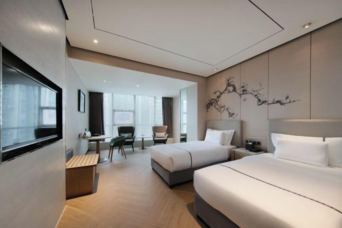 Habitació d'hotel moderna amb dos llits, un escriptori i una cadira.