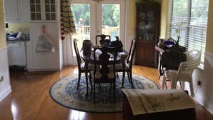 A dining area with a round table, chairs, a chandelier, and a patterned rug.