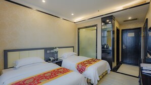 A hotel room with two beds, a nightstand, a mirror, a wardrobe, and a bathroom door.