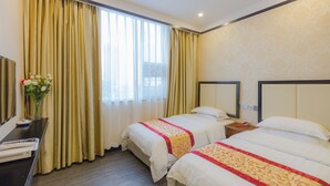 A hotel room with two beds, a desk, and a large window with curtains.