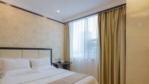 A hotel room with a large bed, a nightstand with a phone, and a window with curtains.